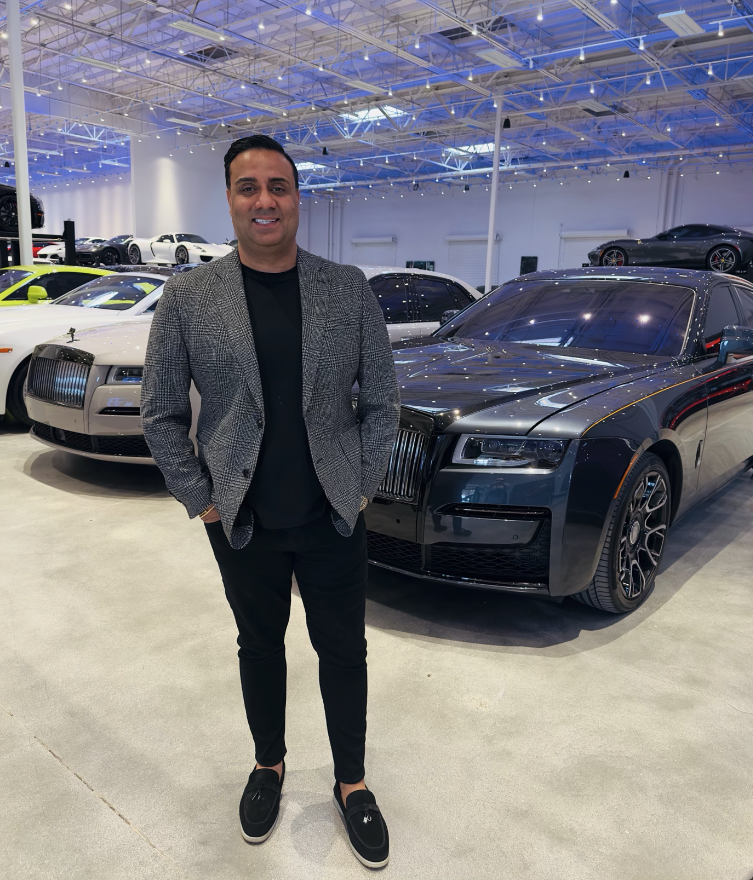 Nick Dossa standing in front of luxury cars at Vegas Auto Gallery showroom